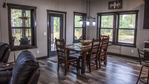 A dining area with a wooden table and chairs, large windows, and a hanging light fixture. - Beautiful Getaway! All paved roads, garage, Snowmobile, Terry Peak, Deadwood (Lead)