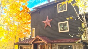 Une cabane rustique ornée d’une grande étoile décorative, dotée de fondations en pierre et d’un garage en bois.