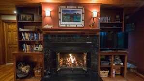 Une cheminée surmontée d’un tableau encadré, entourée d’étagères à livres et d’un téléviseur.