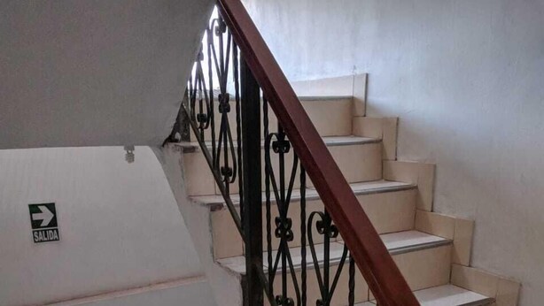 Una escalera con barandilla de metal y un letrero que indica 'SALIDA'.