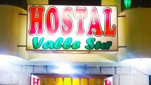 Entrada a un hostal con un cartel que dice "HOSTAL Valle Sur" y varios letreros que indican "HOSTAL" en las puertas.