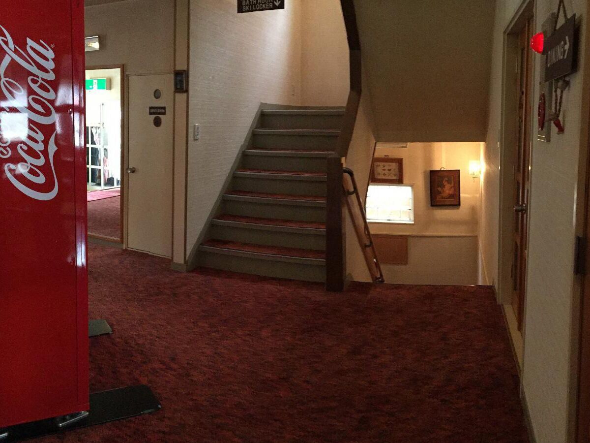 A staircase in a hotel lobby with a Coca-Cola vending machine and a sign indicating a ski locker.