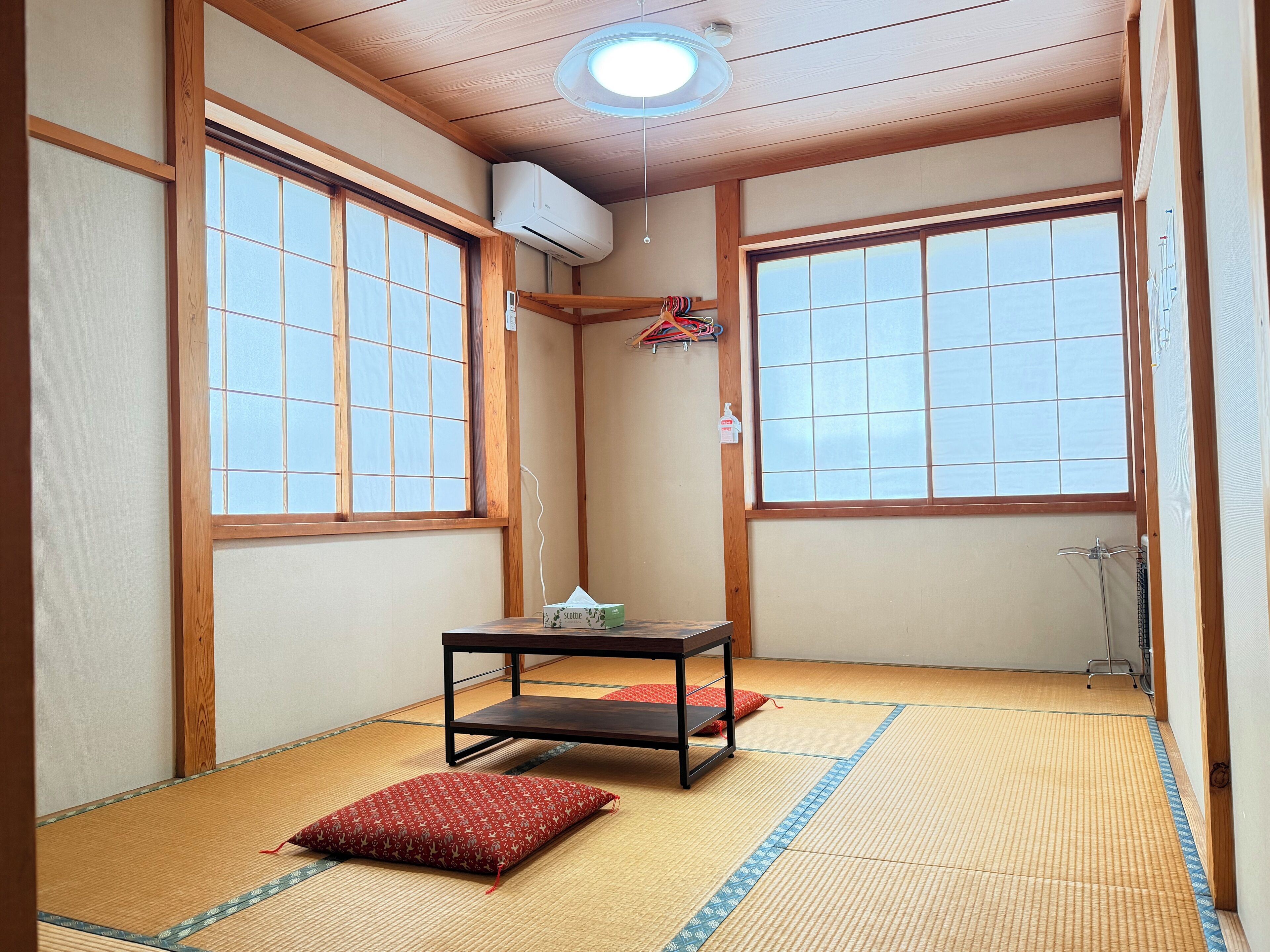 Ein traditioneller japanischer Raum mit Tatami-Böden, einem niedrigen Tisch und einem roten Kissen.