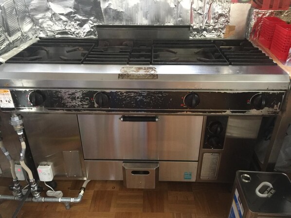 A stainless steel kitchen with a gas stove, oven, and various kitchen appliances. - Kagura House (Yuzawa)