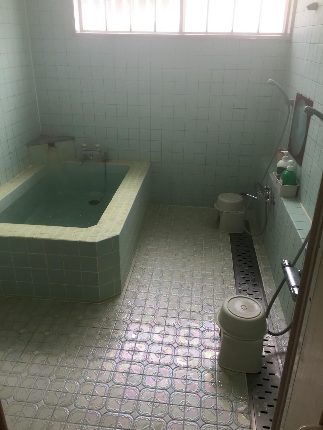 Et badeværelse med badekar, bruser og toilet.