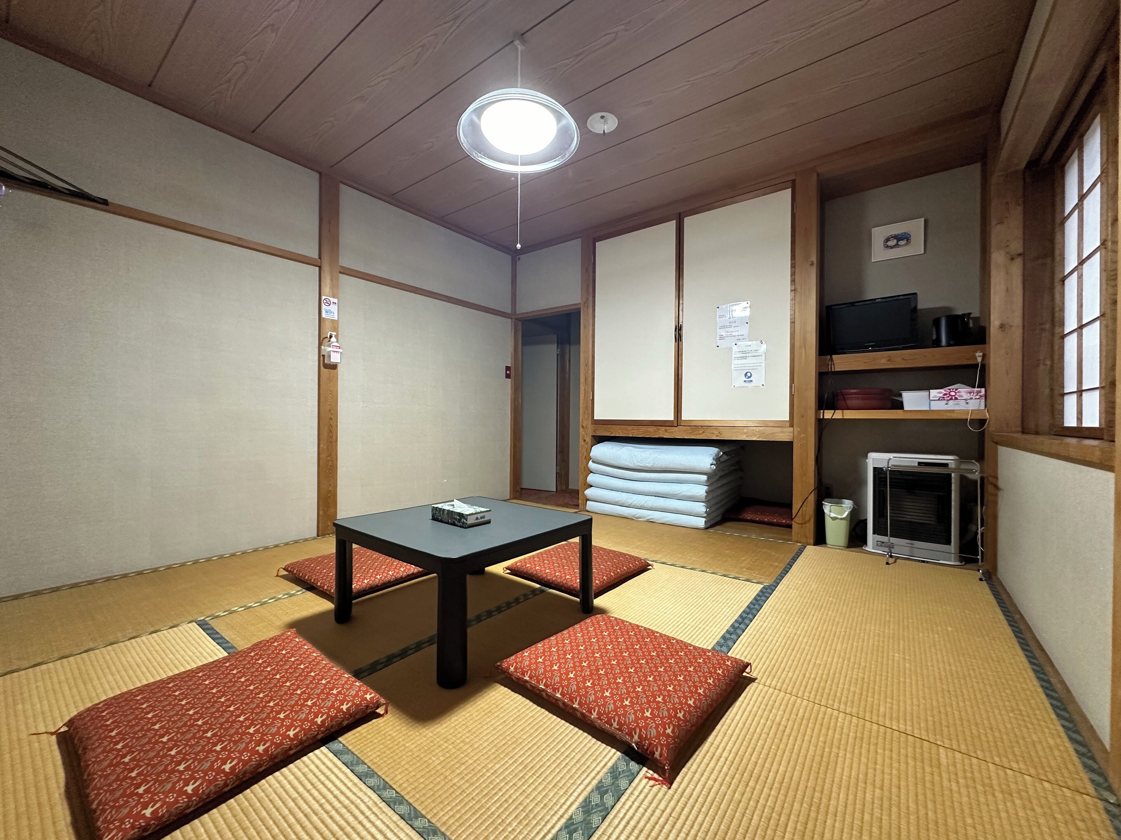 Una habitación japonesa tradicional con suelo de tatami, una mesa baja y cojines.