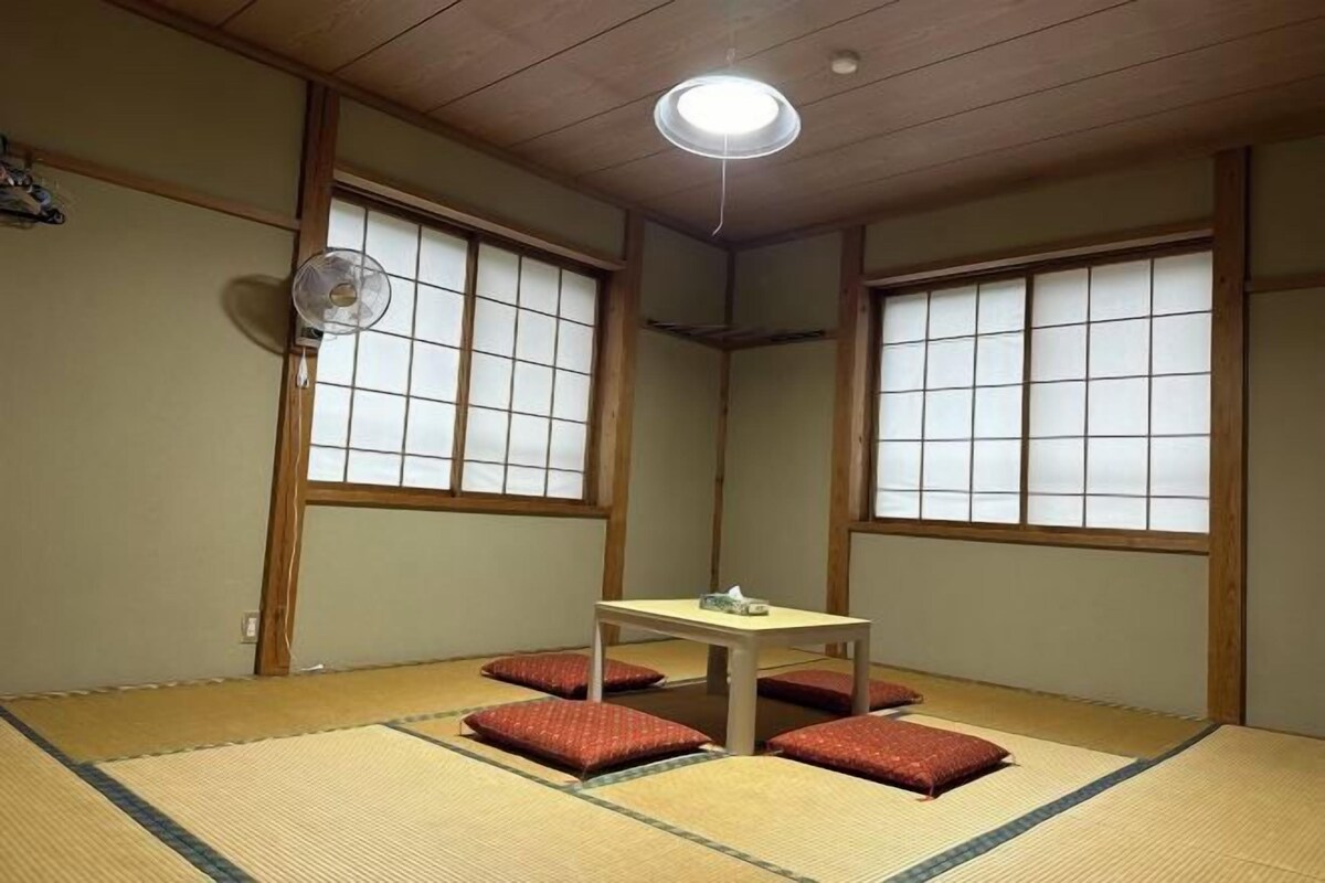 Una habitación japonesa tradicional con suelo de tatami, una mesita baja y puertas correderas.