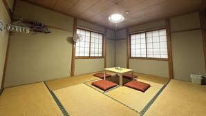 A traditional Japanese room with tatami flooring, a low table with cushions, and sliding shoji doors. - Kagura House (Yuzawa)