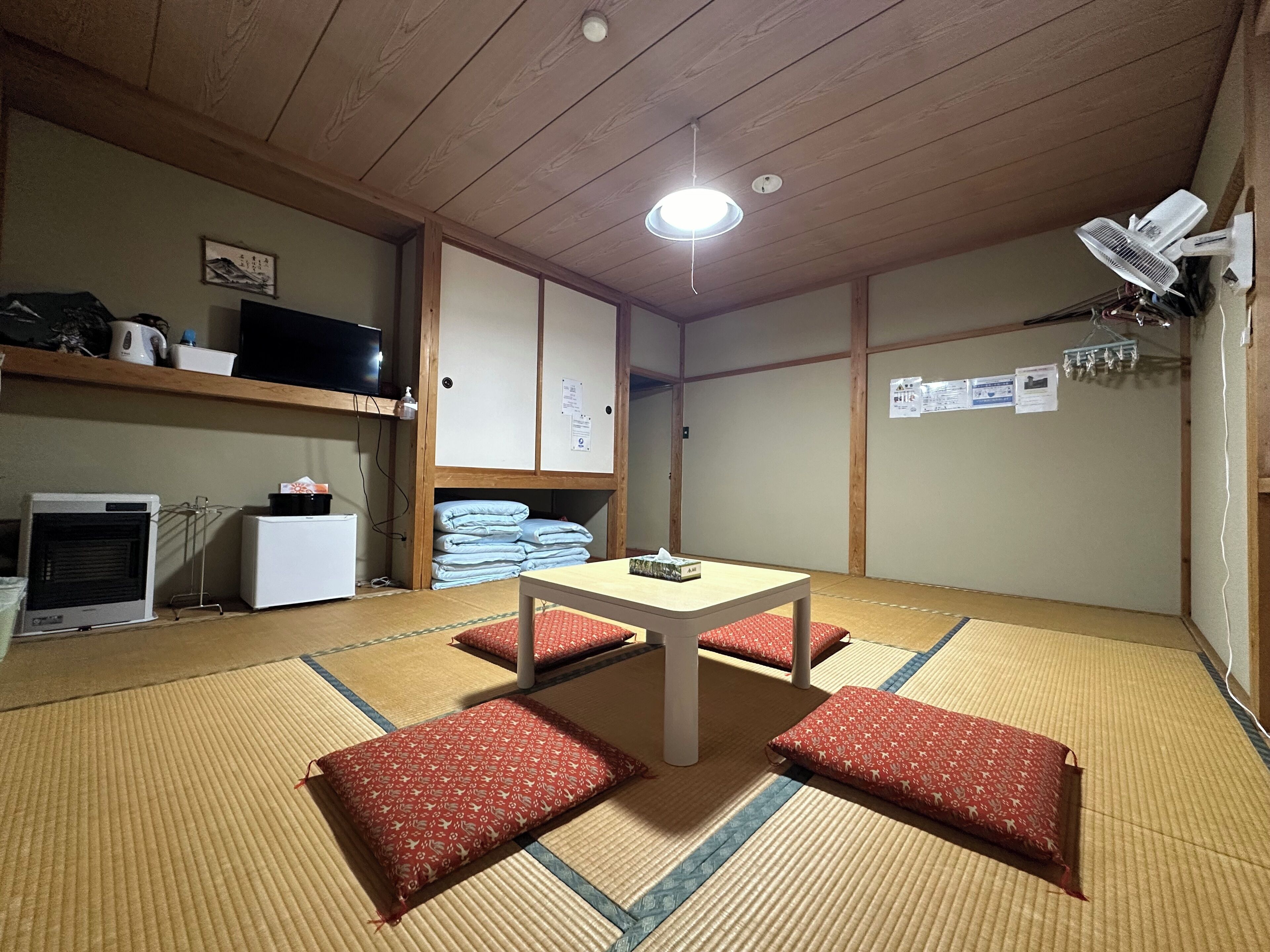 Une pièce de style japonais traditionnel, avec un sol recouvert de tatamis, une table basse et des coussins rouges.