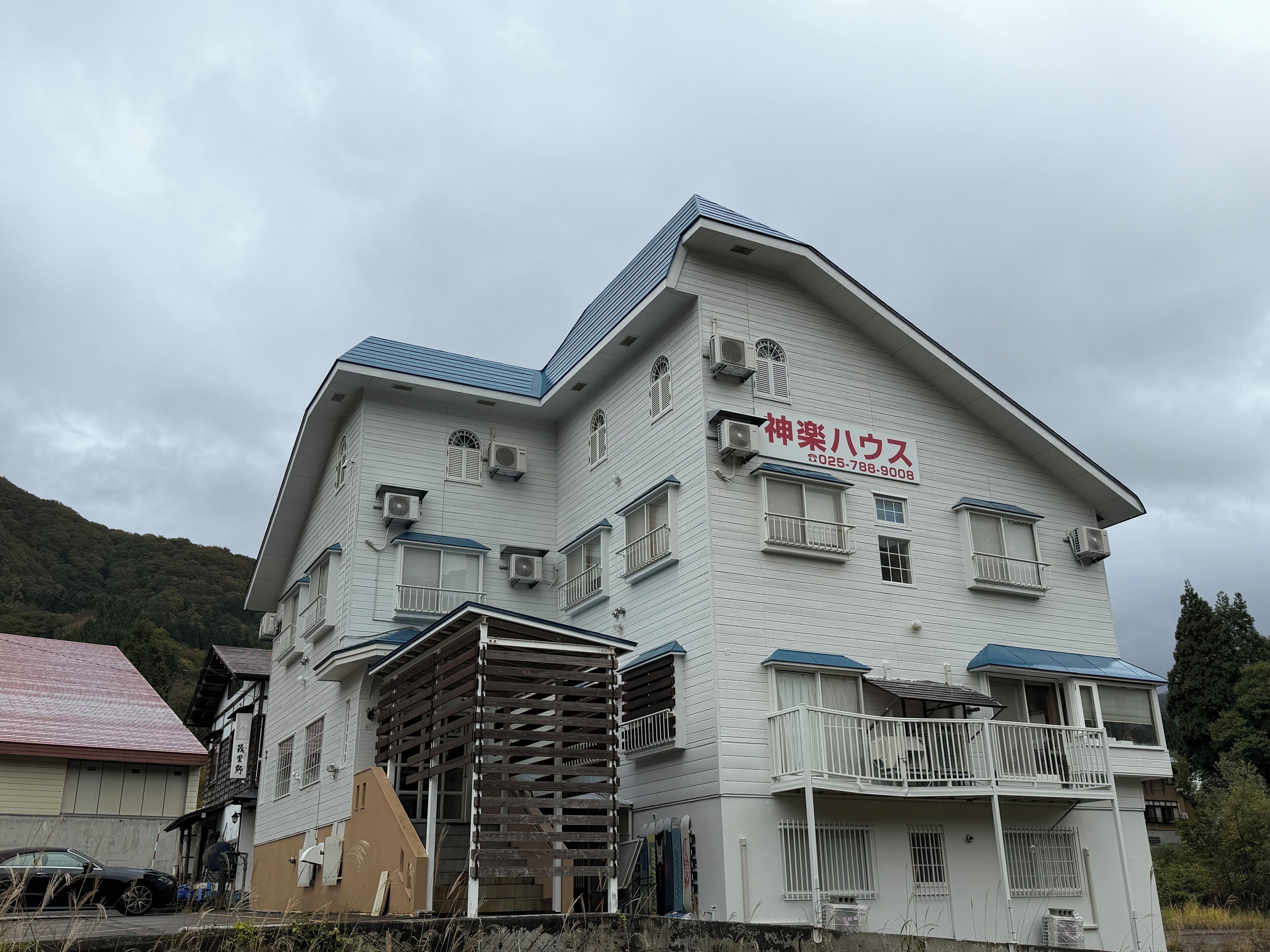 A multi-story building with a sign in Japanese, air conditioning units, and a balcony.