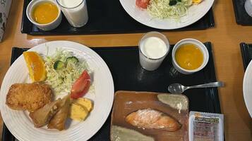 A dining table with plates of food, including breaded fish, vegetables, and a variety of side dishes.