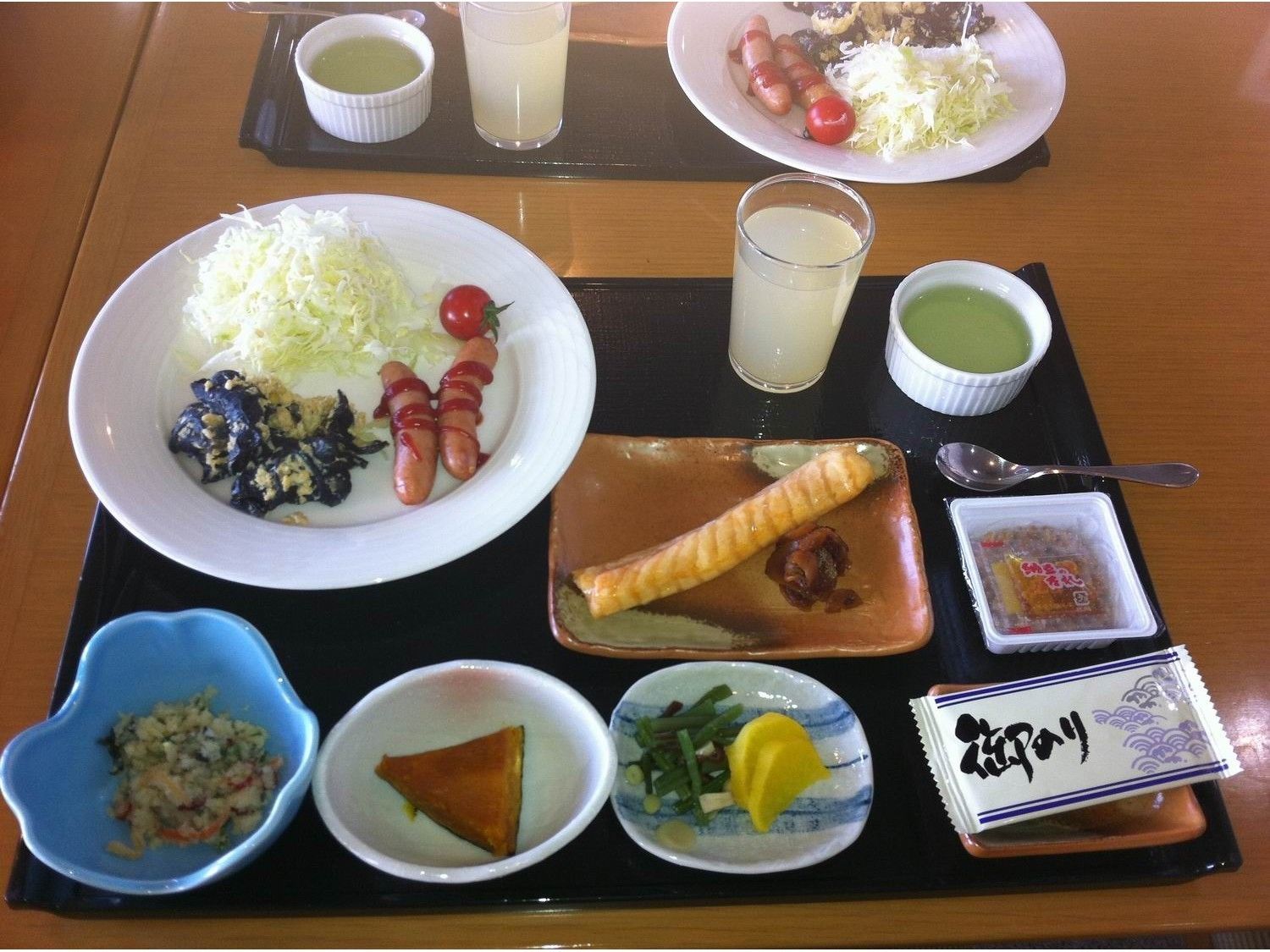 A table with various dishes including a plate with cabbage, sausages, and a bowl of pickled vegetables.