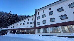 Un edificio de varios pisos con ventanas amplias y techo plano, rodeado de nieve.