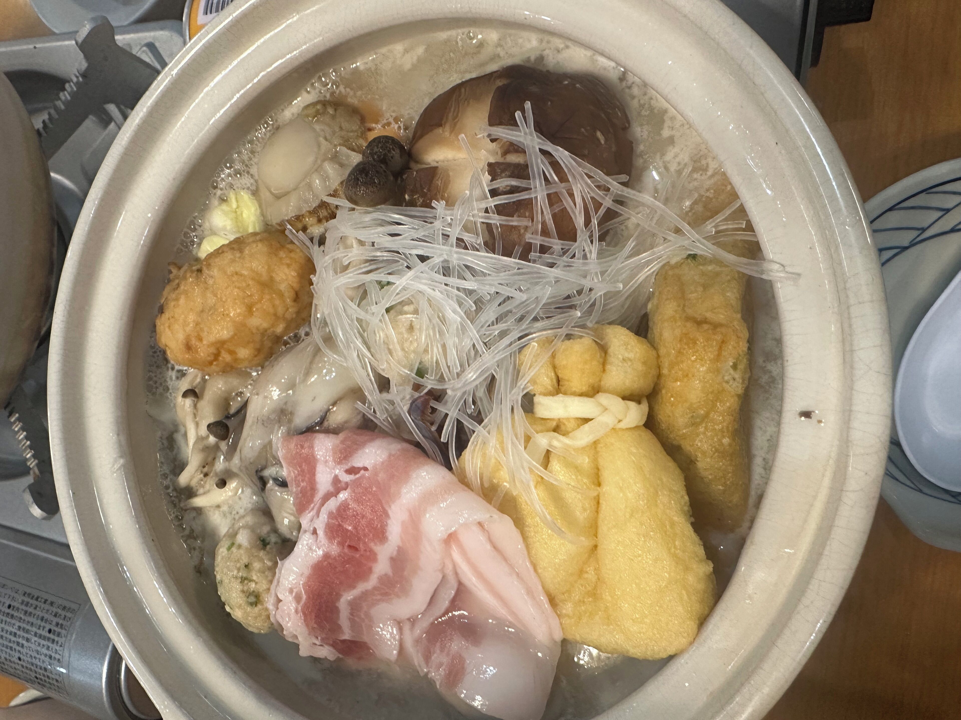 A bowl of ramen with various toppings including noodles, meat, and vegetables.