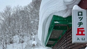 Un edificio cubierto de nieve con techo verde y un letrero en japonés.