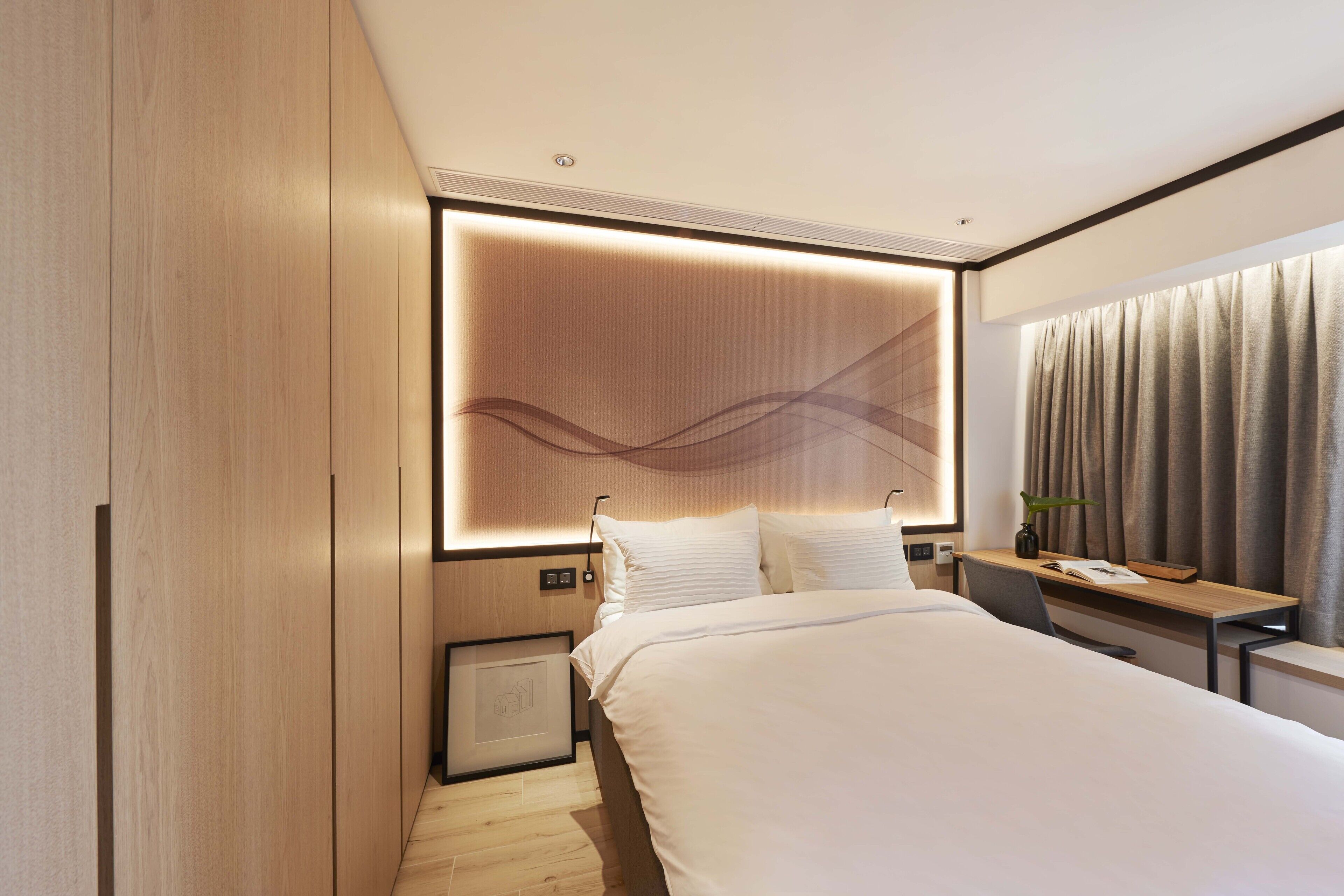 A modern hotel room with a large bed, a desk, and a wall-mounted TV.