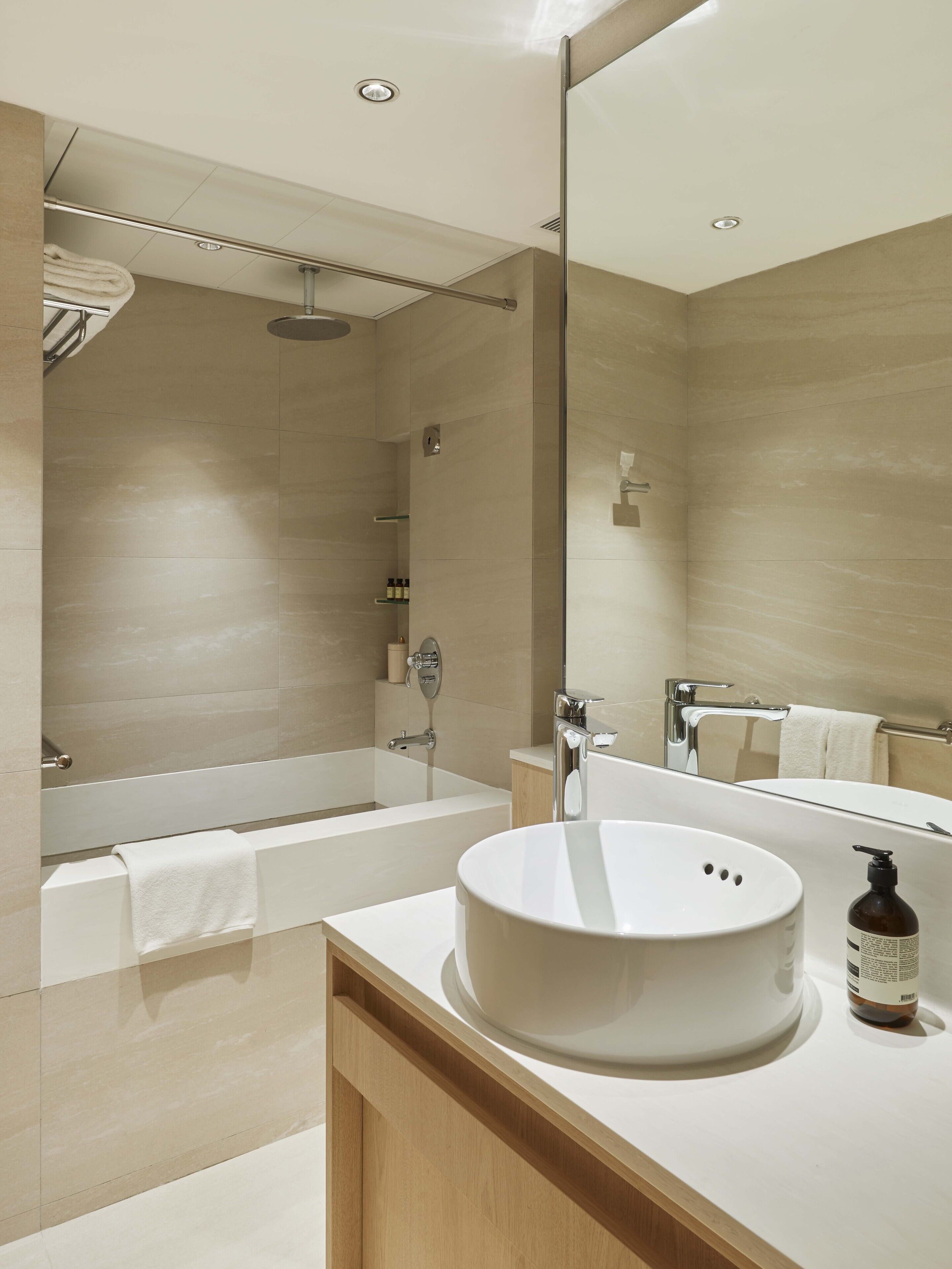 Un baño moderno con una bañera grande, un lavabo redondo y una cabina de ducha con paredes de vidrio.