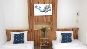 Habitación de hotel con dos camas, una pared de madera, un cuadro y una mesita con una planta.