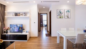 A modern living room with a TV, bookshelf, and dining area.