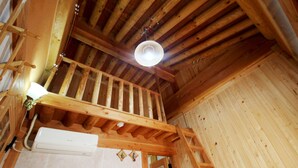 A wooden interior with a balcony, a white air conditioning unit, and a wooden door. - Doldam House (Jeonju)