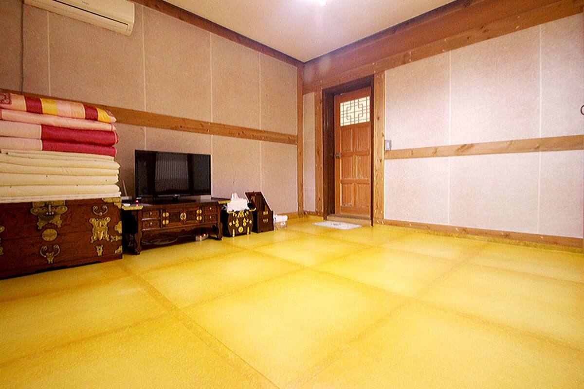 A traditional Japanese room with tatami flooring, a television, and a wooden door.