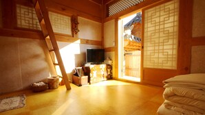 A traditional Japanese room with tatami flooring, a television, and sliding doors. - Doldam House (Jeonju)