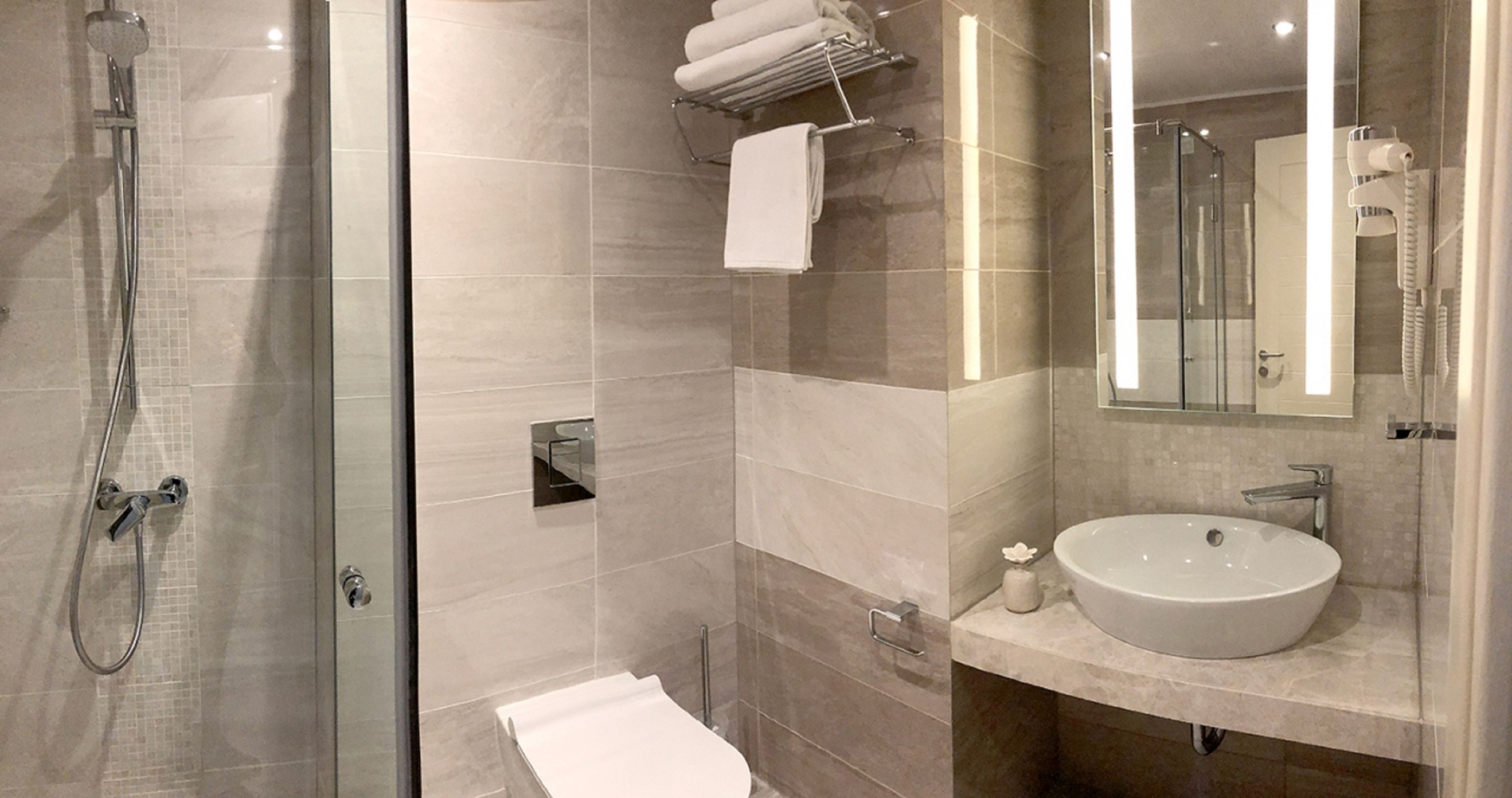 A modern bathroom with a glass-enclosed shower, a white sink, and a large mirror.
