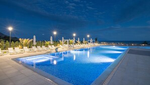 A swimming pool with lounge chairs and umbrellas, surrounded by a tiled deck and palm trees. - King Maron Beach Hotel & Spa (Maroneia-Sapes)