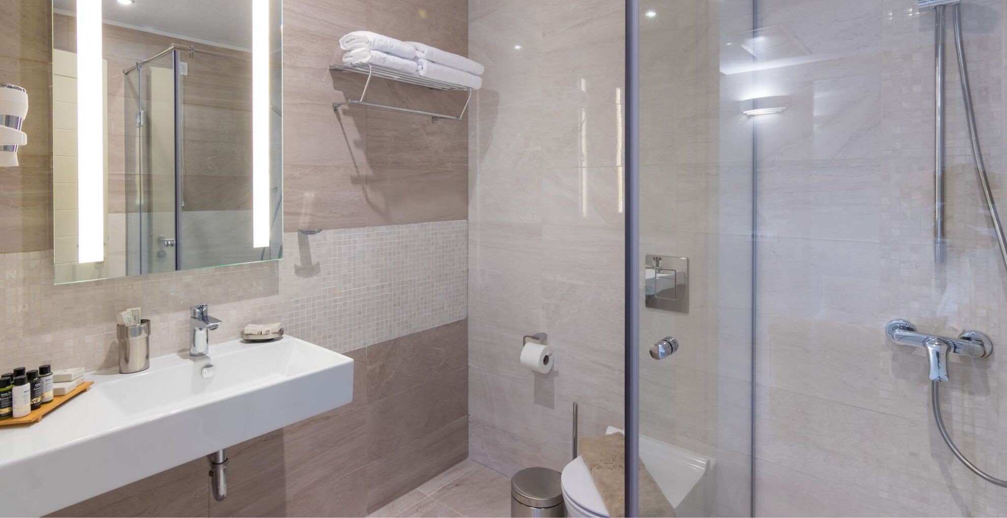 A modern bathroom with a glass shower enclosure, a white sink, and a mirror.