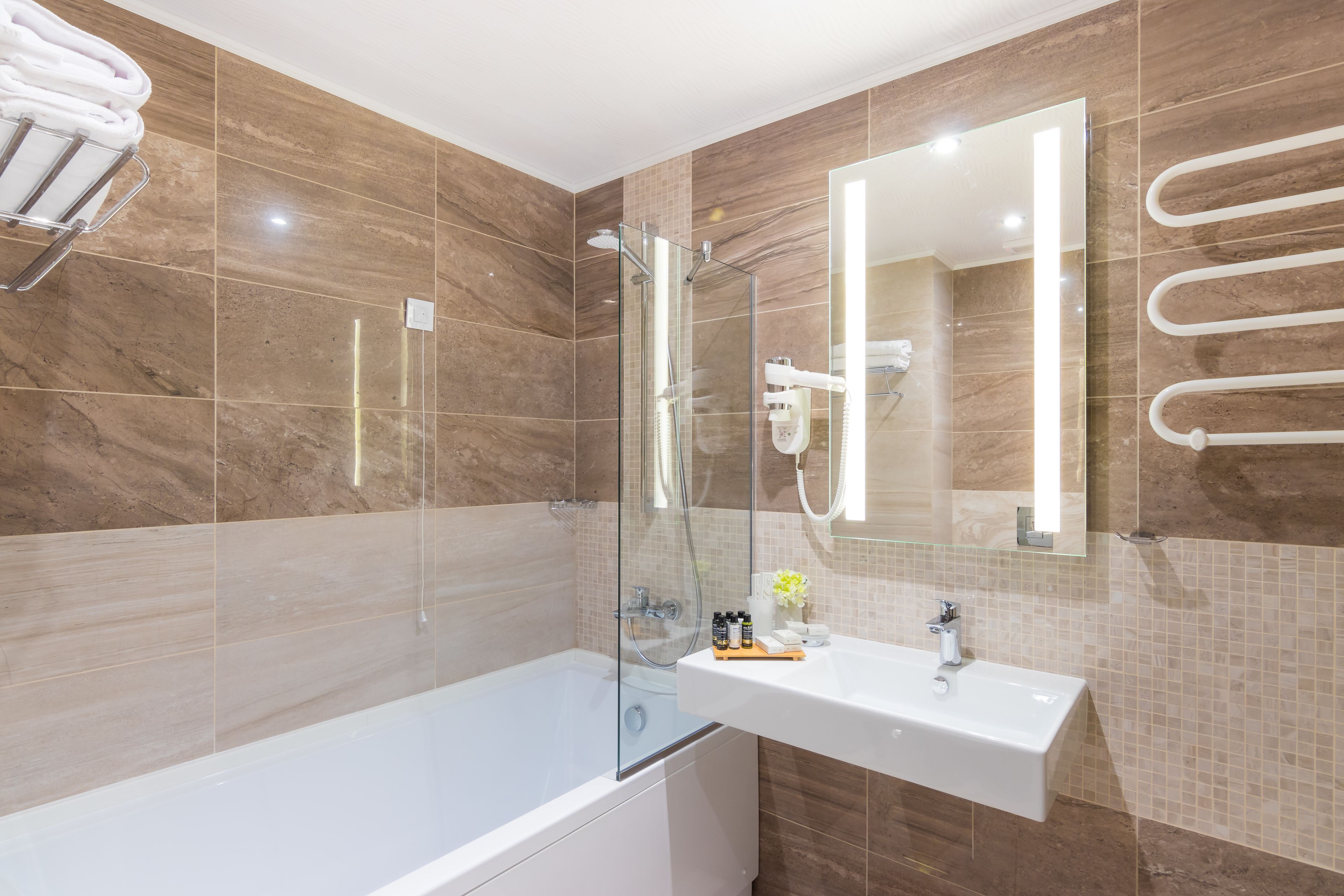 A modern bathroom with a glass-enclosed shower, a white sink, and a towel rack.