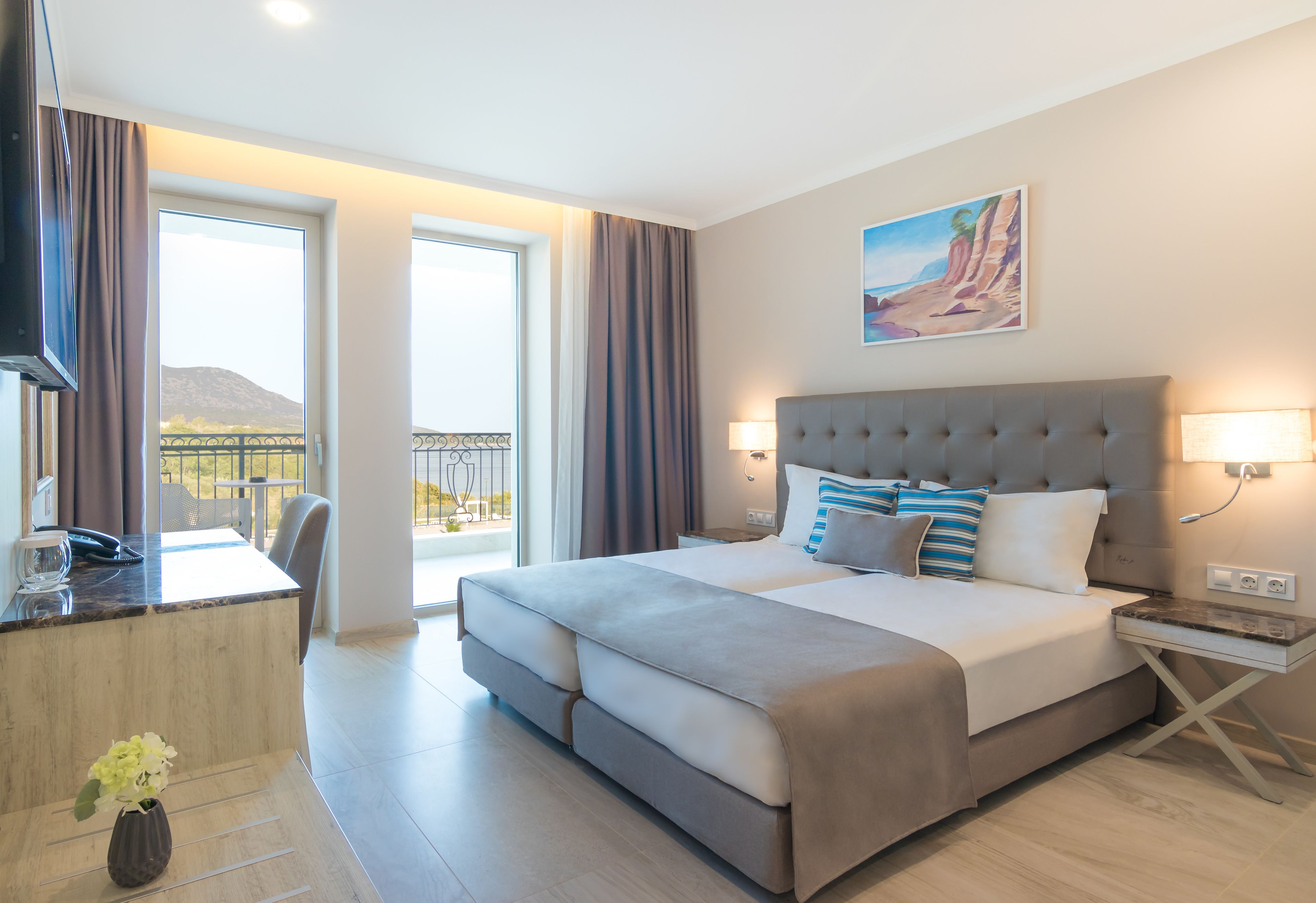 Una habitación de hotel moderna con una cama grande, un escritorio y un balcón con vistas a las montañas.