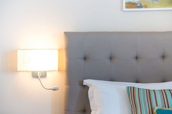 A neatly made bed with a grey headboard, white pillows, and a striped pillow.