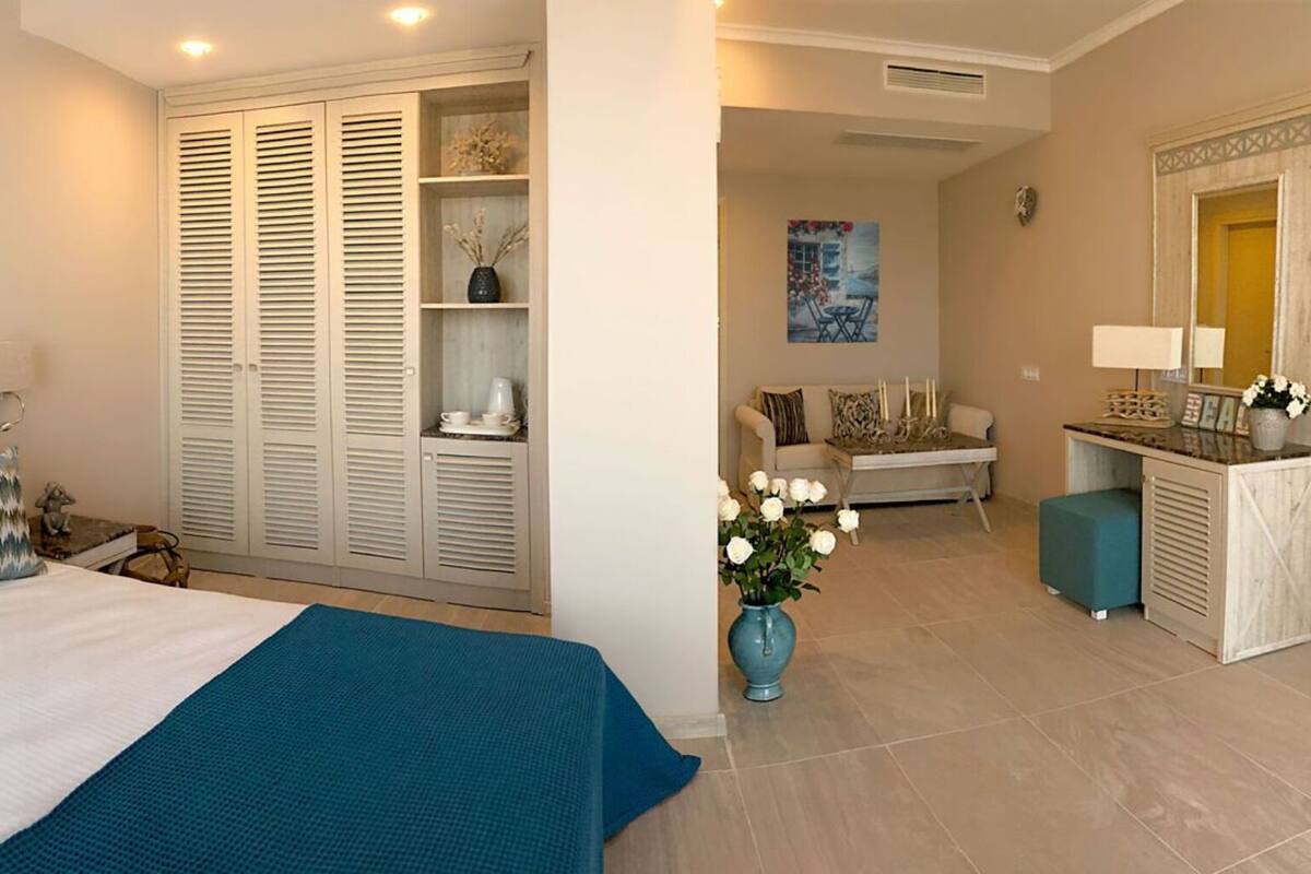 Un dormitorio con cama, armario, escritorio y baño.
