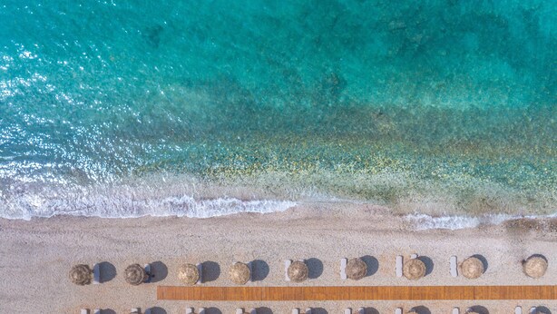 An aerial view of a beach with rows of sun loungers and a wooden deck. - King Maron Beach Hotel & Spa (Maroneia-Sapes)