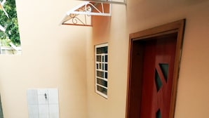 A hallway with a patterned floor, a red door, and a small window. - Residence 2 Pièces Duplex (Abidjan)