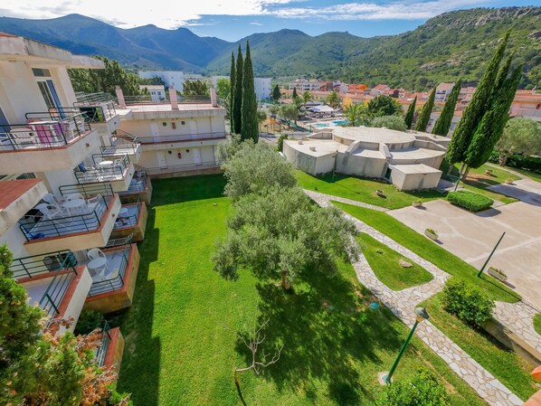 A courtyard with a swimming pool, surrounded by buildings with balconies and a mountainous backdrop. - Agi Rescator 205 Apartamento for rent in Roses Girona. (Rosas / Roses)