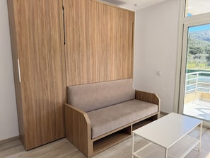 A modern room with a wooden wardrobe, a beige sofa, and a small white table.