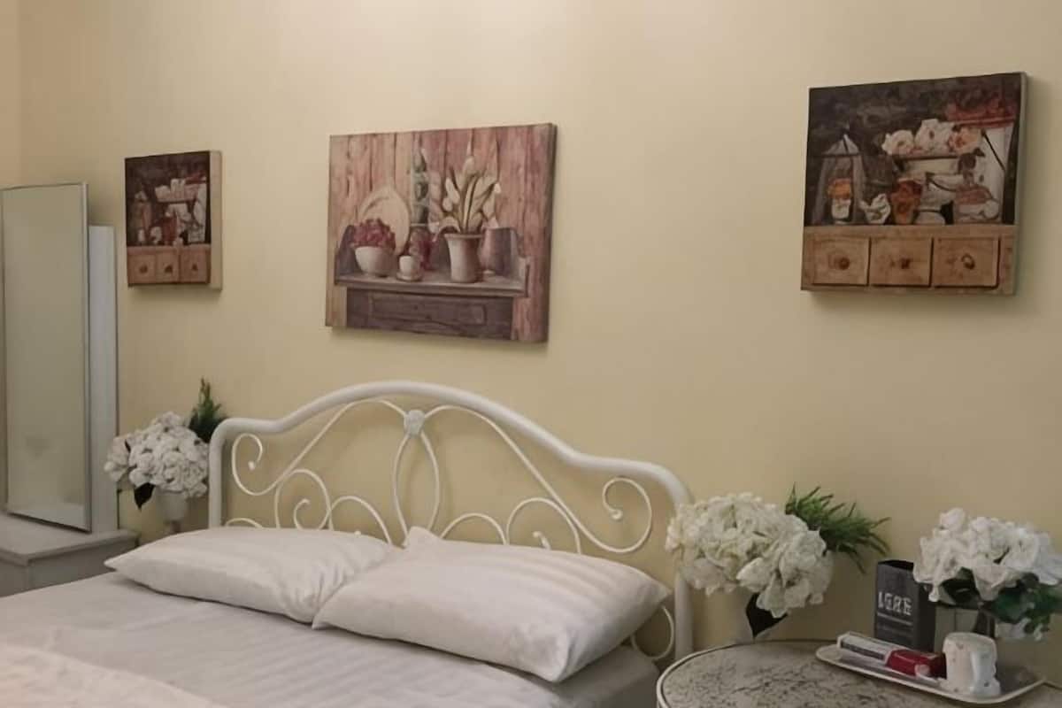 A bedroom with a bed, a mirror, and wall-mounted artwork.