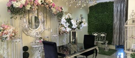 Una habitación lujosa con candelabro, espejo decorado y arreglos florales.