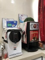 A coffee machine and a Gula Cup Pack sign on a counter.
