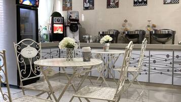 A modern kitchen with a central island, white chairs, and a refrigerator.