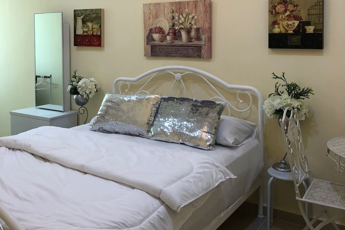 A bedroom with a bed, a nightstand, a mirror, and wall art.
