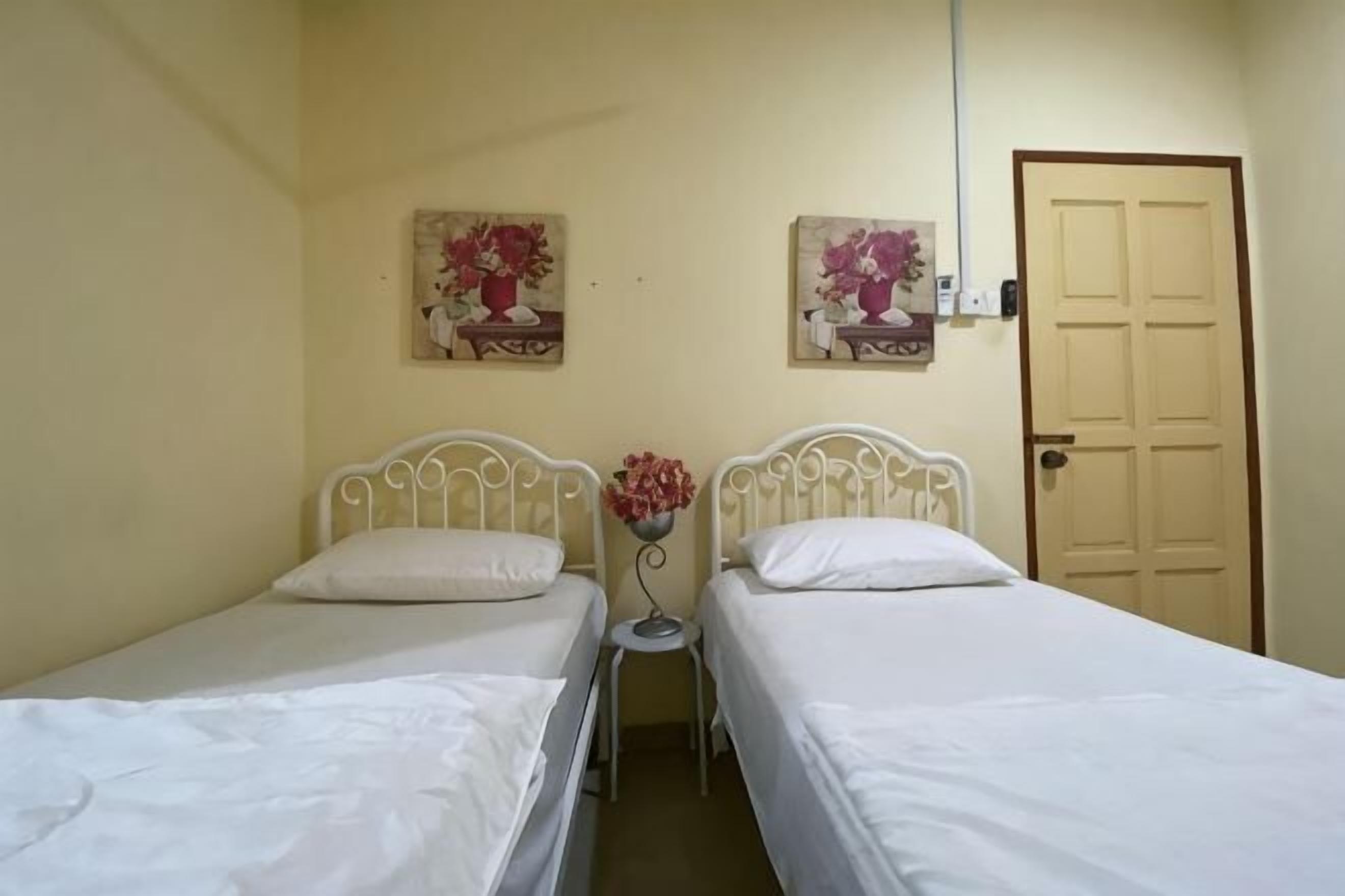 A room with two single beds, a door, and two wall-mounted paintings.