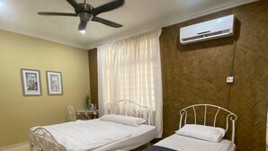 Una habitación con dos camas de metal, un ventilador de techo, un equipo de aire acondicionado y piso de baldosas.