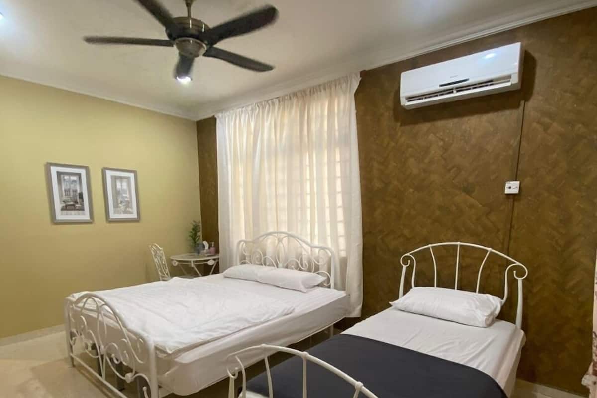 A room with two metal beds, a ceiling fan, an air conditioning unit, and a tiled floor.