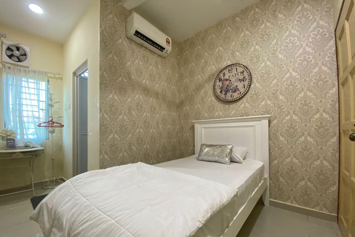 A bedroom with a bed, a wall clock, and an air conditioning unit.