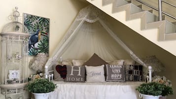 Un dormitorio acogedor con cama a dosel, cojines decorativos, una jaula de pájaros y una escalera.