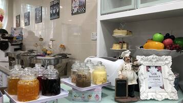 A kitchen area with stainless steel cooking equipment, jars of condiments, a decorative chef figurine, and a fruit display.