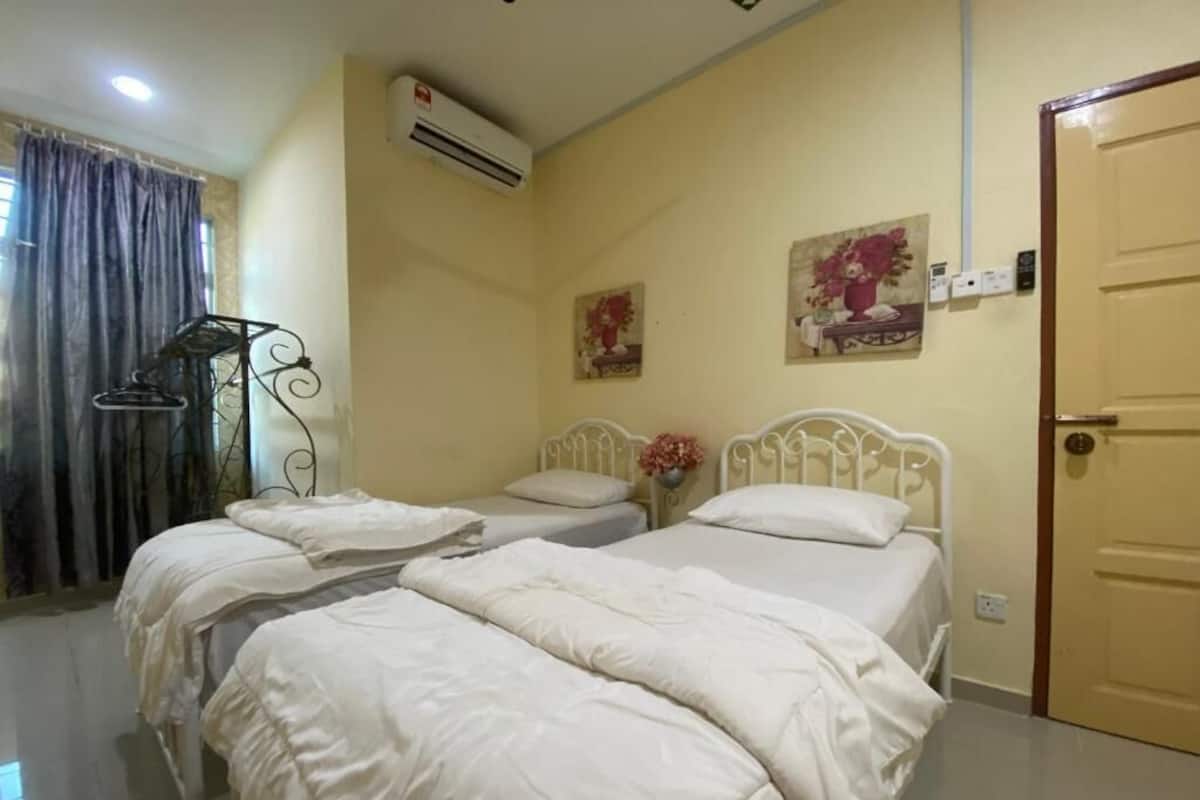 A room with three beds, an air conditioning unit, a door, and two wall-mounted paintings.