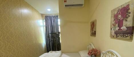 Una habitación con dos camas individuales, ventilador de techo, aire acondicionado y un cuadro en la pared.